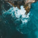 Fotografía aérea de olas rompiendo sobre un acantilado rocoso junto al mar.